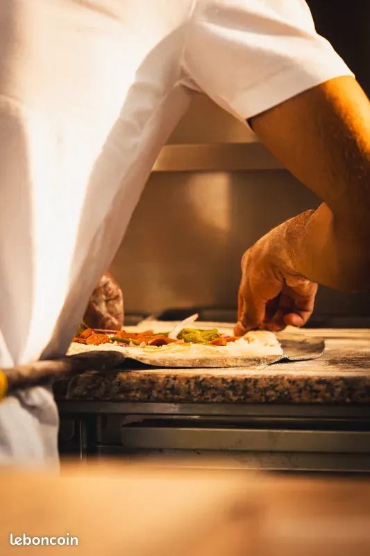 Pizzaïolo garnissant une pâte sur le plan de travail